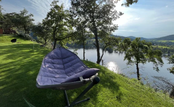 A hammock on the lawn above the lake, in afternoon sun